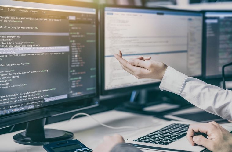 Developers reviewing application code on multiple monitors